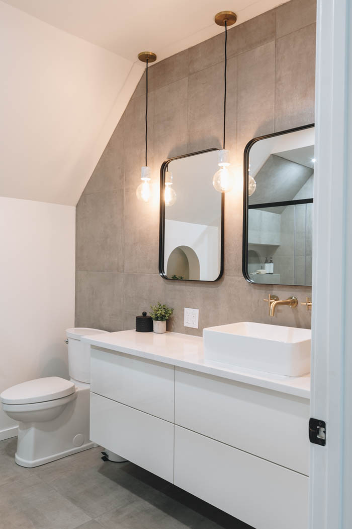 Modern renovated bathroom with grey tile and gold fixtures